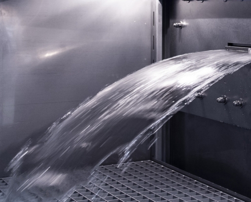 Schwallwasserprüfung: Ein Wasserschwall schießt aus der Schwalldüse in den Prüfraum der Schwallwasserkammer