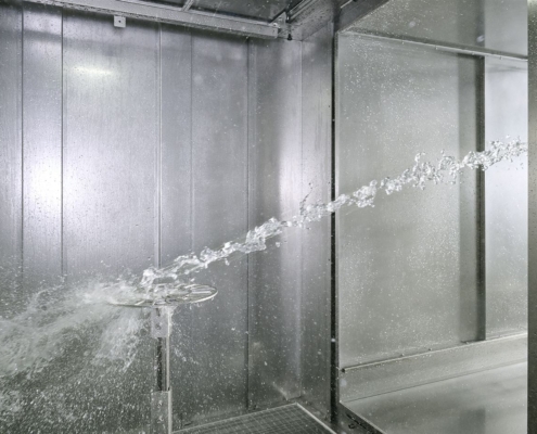Strahlwasserprüfung in einer iTS-Spritzwasserkammer SPK: Der Wasserstrahl kommt aus dem Anbautunnel und trifft auf den Drehteller
